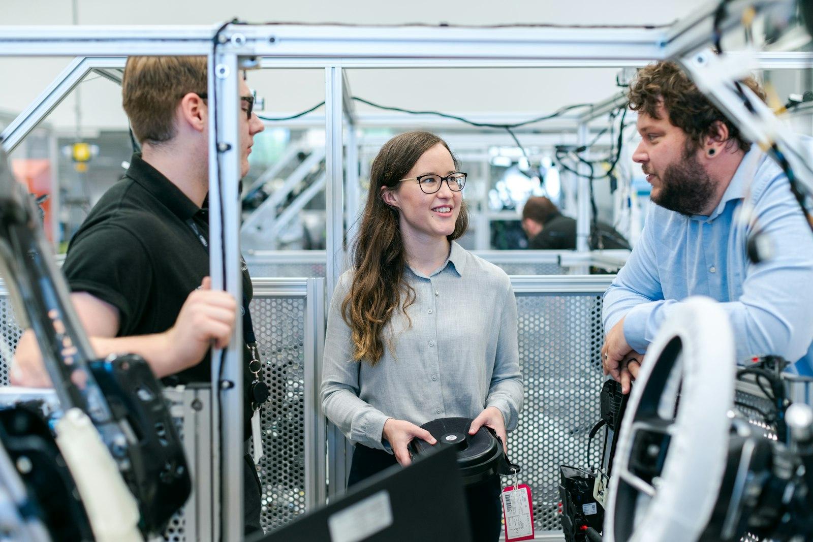 Three engineers talking around a prototype test rig in an R&D lab