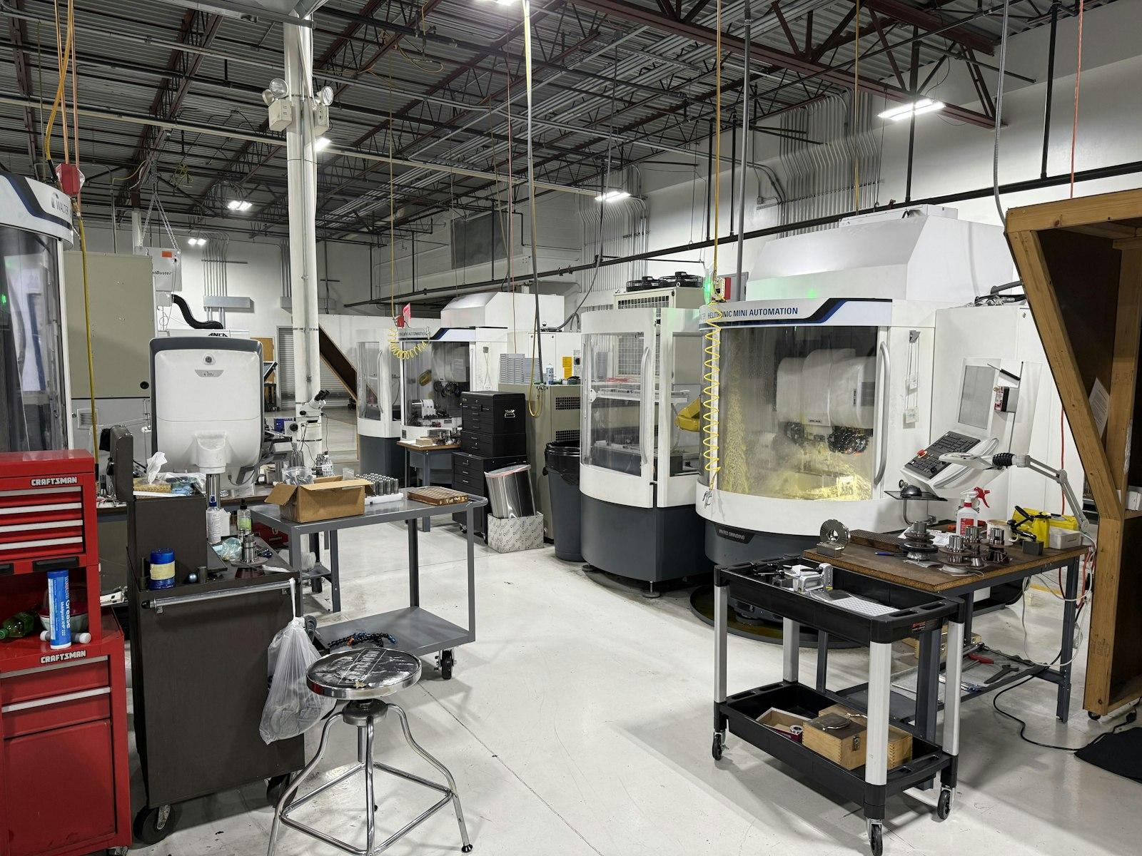 Machine shop floor with CNC tool-grinding cells, workbenches and tool carts